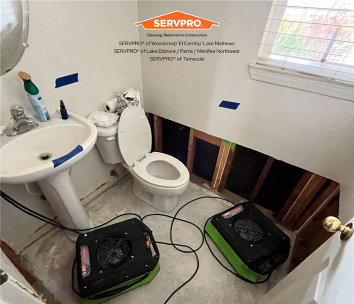 a water damaged bathroom with the walls and hardwood flooring taken out and airmovers placed on floor